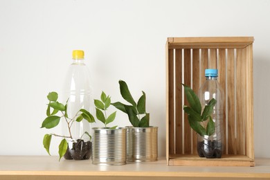 Photo of Recycling concept. Metal cans and plastic bottles with plants on wooden table