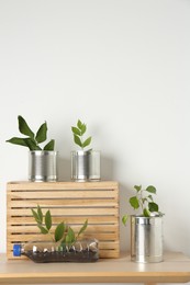 Photo of Recycling concept. Metal cans and plastic bottle with plants on wooden table