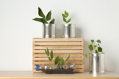 Photo of Recycling concept. Metal cans and plastic bottle with plants on wooden table