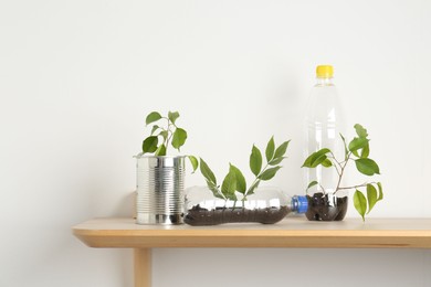 Photo of Recycling concept. Metal can and plastic bottles with plants on wooden table