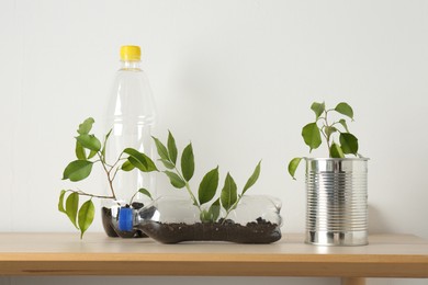 Photo of Recycling concept. Metal can and plastic bottles with plants on wooden table