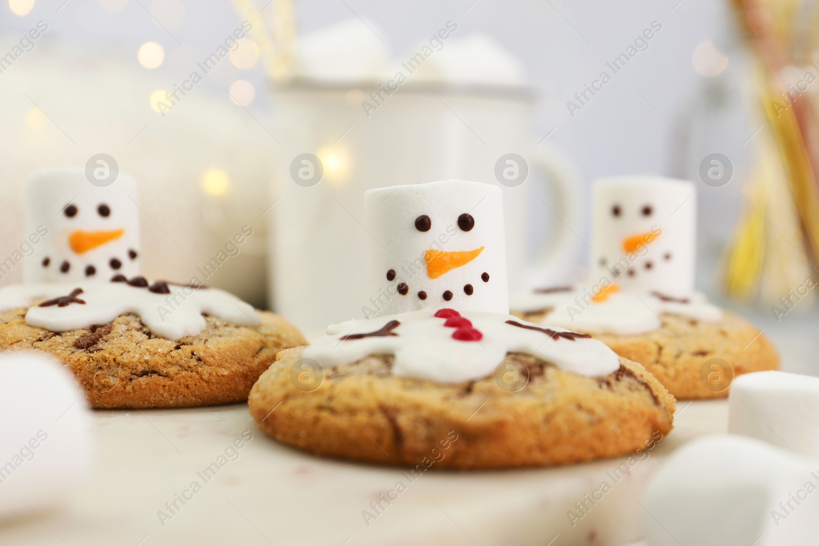 Photo of Delicious cookies with snowmen made of marshmallows on white table, closeup