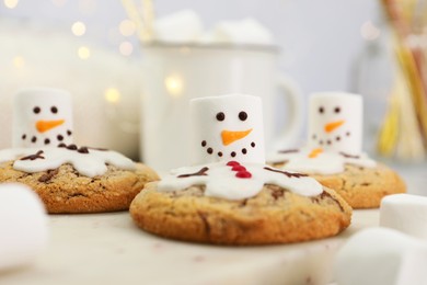 Photo of Delicious cookies with snowmen made of marshmallows on white table, closeup