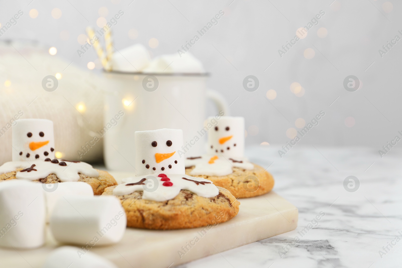 Photo of Delicious cookies with snowmen made of marshmallows on white table, closeup