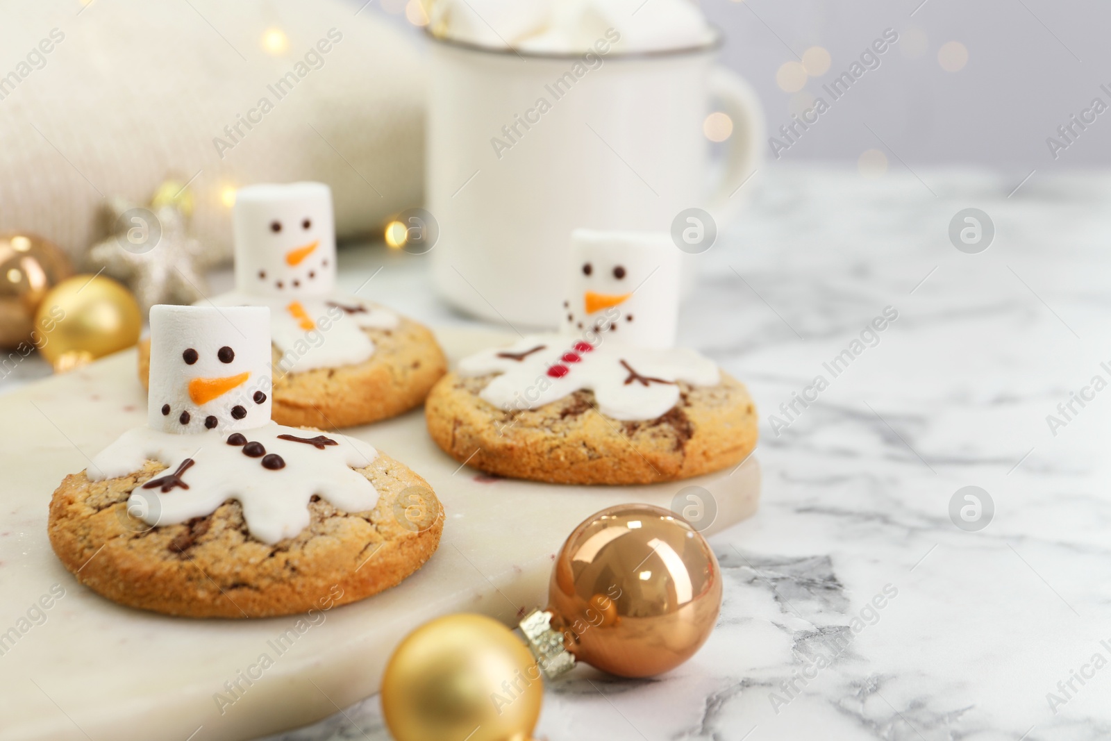 Photo of Delicious cookies with snowmen made of marshmallows on white table, closeup