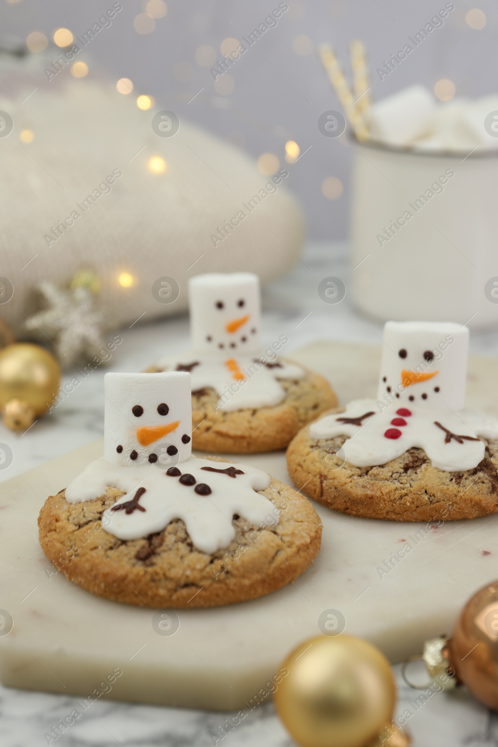 Photo of Delicious cookies with snowmen made of marshmallows on white table, closeup