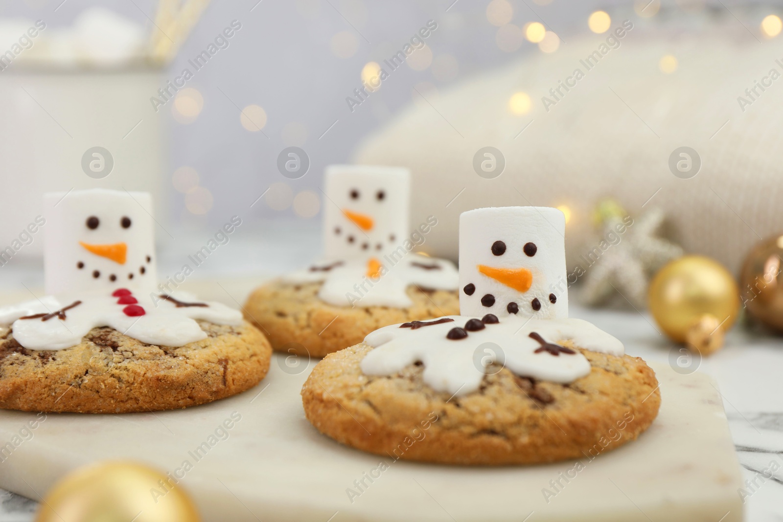 Photo of Delicious cookies with snowmen made of marshmallows on white table, closeup