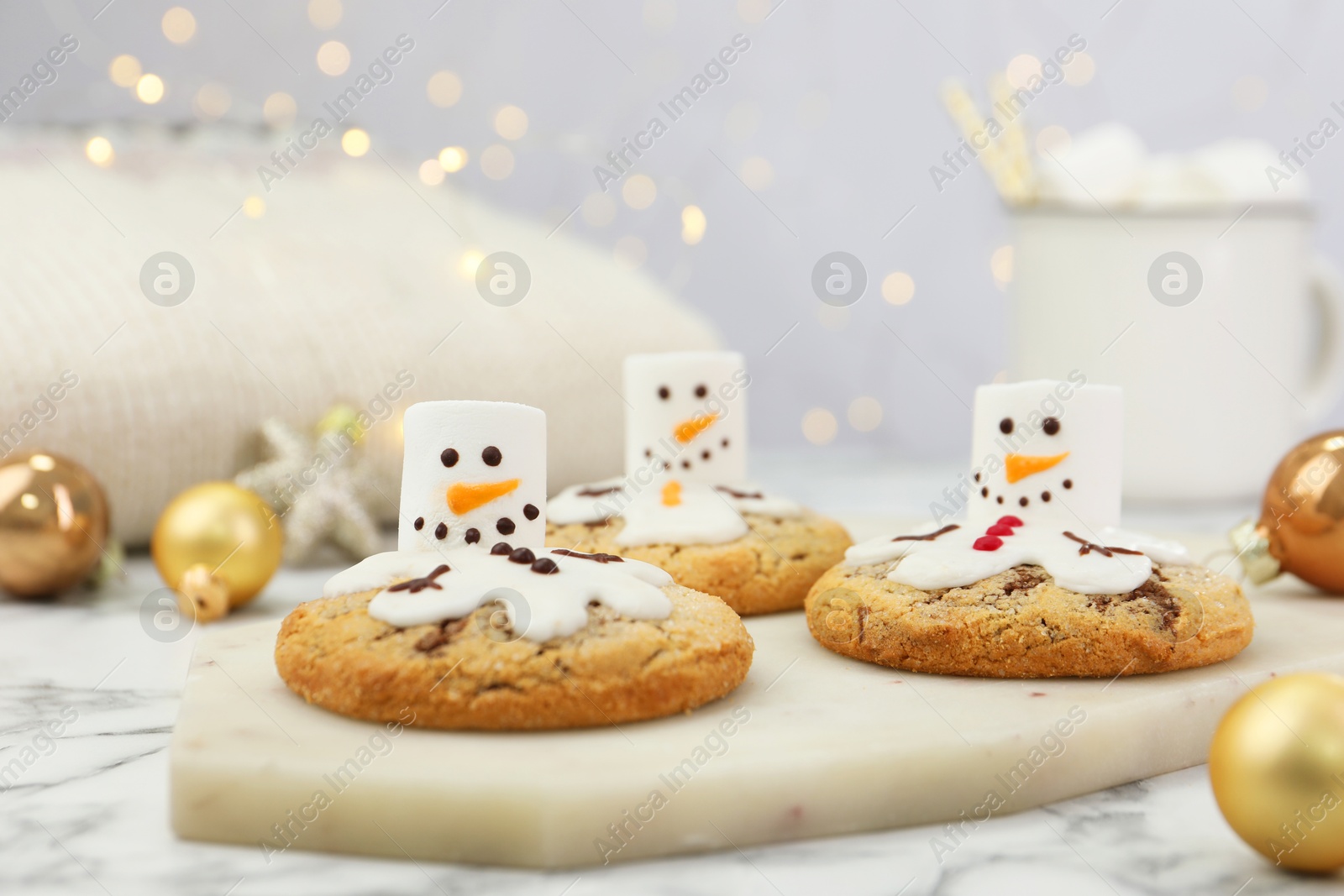 Photo of Delicious cookies with snowmen made of marshmallows on white table, closeup