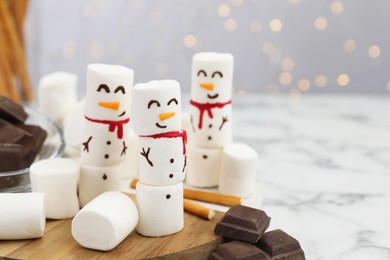 Photo of Funny snowmen made with marshmallows on white marble table, closeup