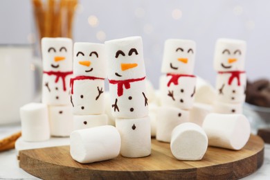 Photo of Funny snowmen made with marshmallows on white table, closeup