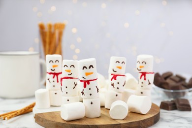 Photo of Funny snowmen made with marshmallows on white marble table