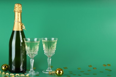 Photo of Sparkling wine, confetti and other Christmas decor on green background. Space for text