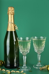 Photo of Sparkling wine, confetti and other Christmas decor on green background