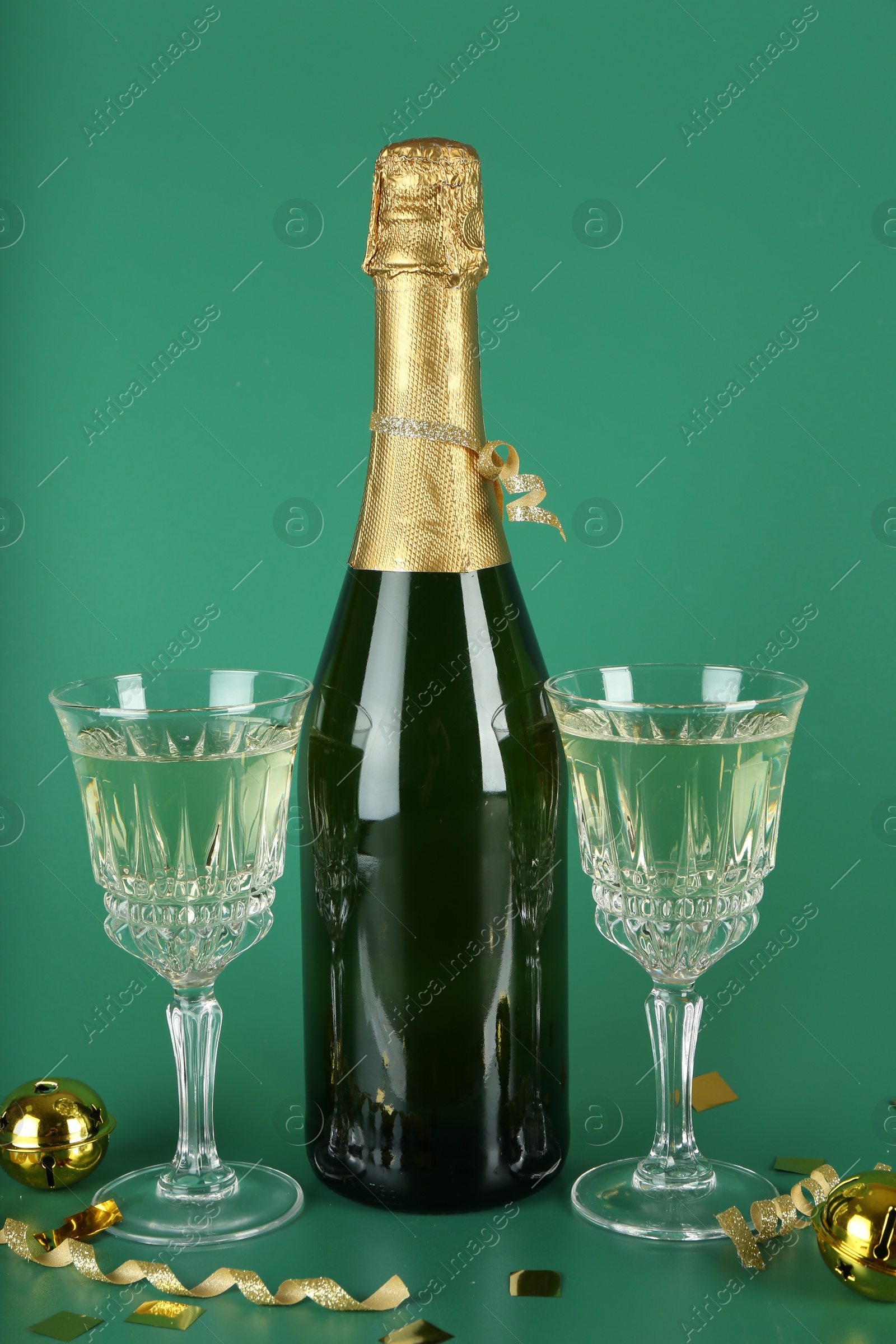 Photo of Sparkling wine, confetti and other Christmas decor on green background