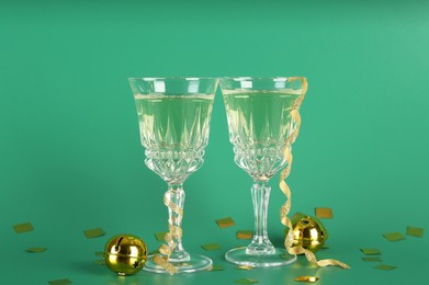 Photo of Sparkling wine in glasses, confetti and other Christmas decor on green background