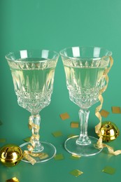 Photo of Sparkling wine in glasses, confetti and other Christmas decor on green background