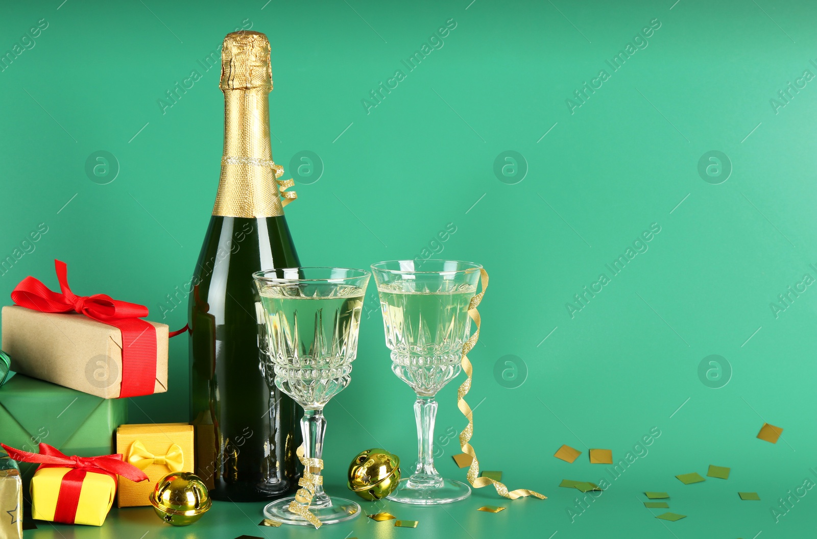 Photo of Sparkling wine, confetti and other Christmas decor on green background. Space for text