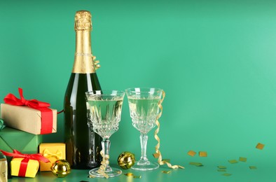 Photo of Sparkling wine, confetti and other Christmas decor on green background. Space for text