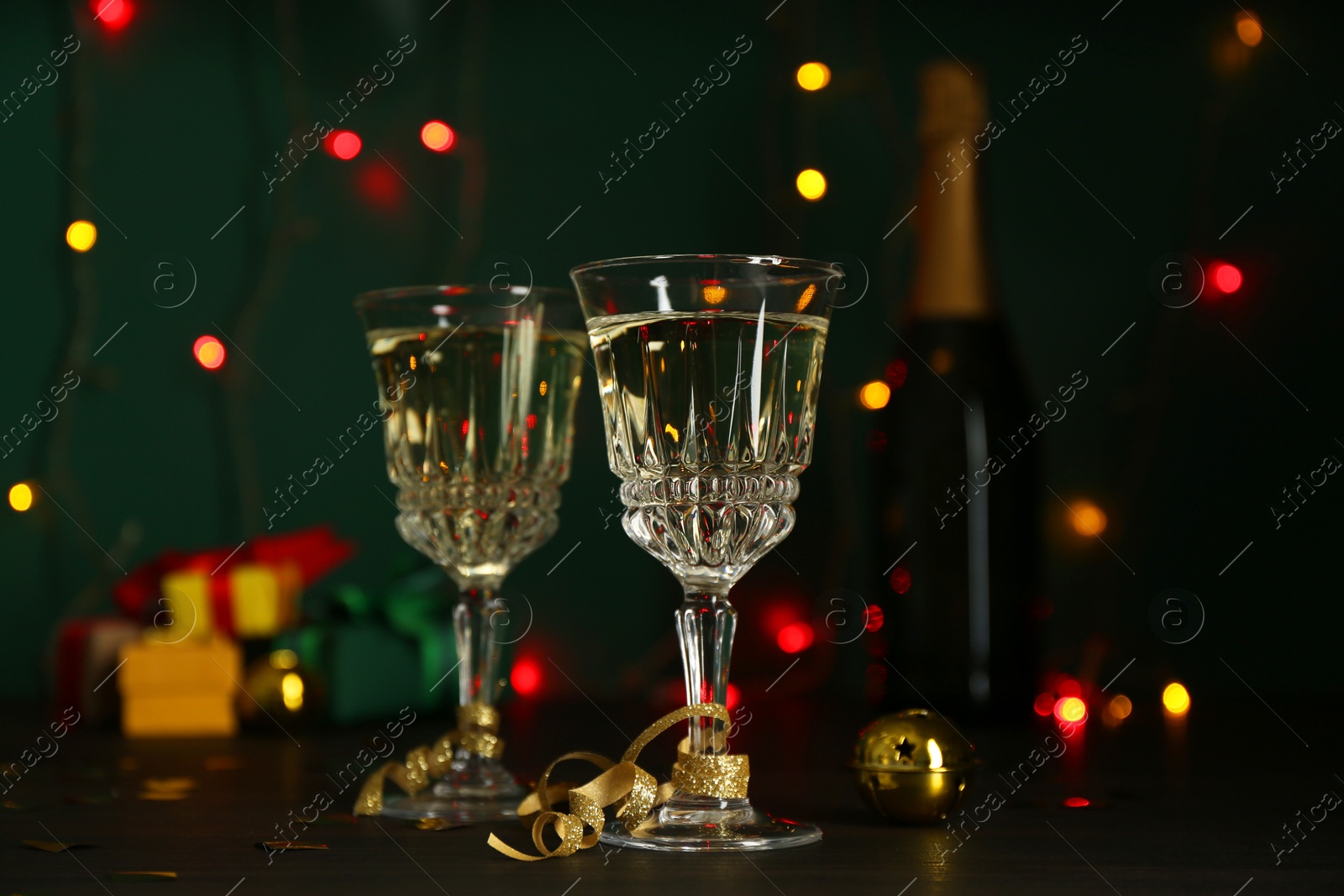 Photo of Glasses of sparkling wine on table against blurred lights