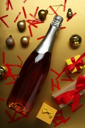 Photo of Flat lay composition with bottle of sparkling wine, confetti and other Christmas decor on beige background