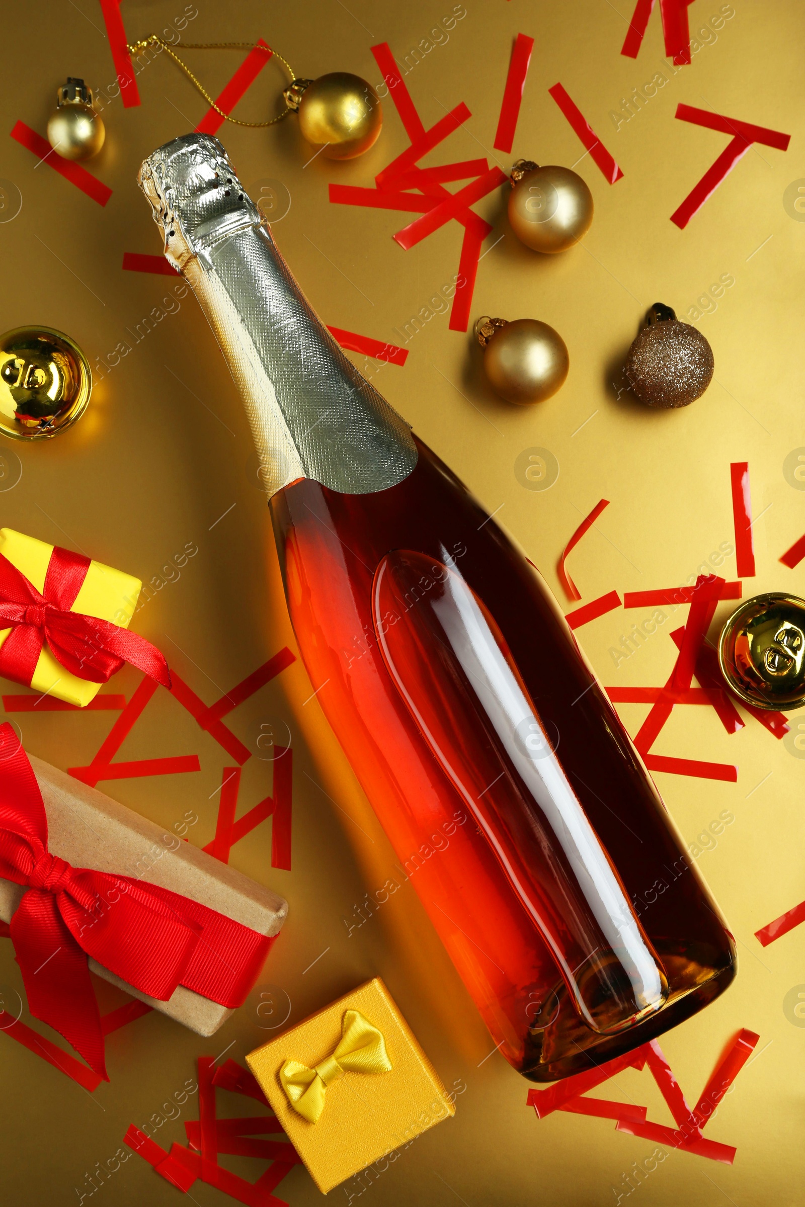 Photo of Flat lay composition with bottle of sparkling wine, confetti and other Christmas decor on beige background