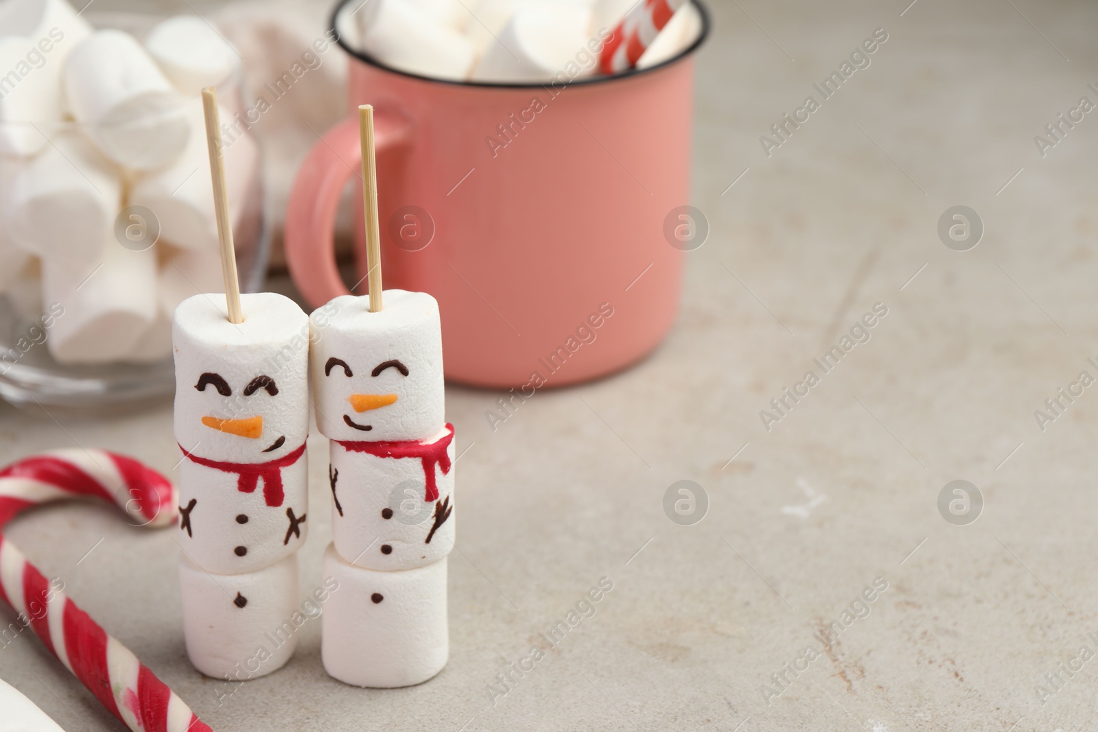 Photo of Funny snowmen made of marshmallows and other sweets on light table. Space for text