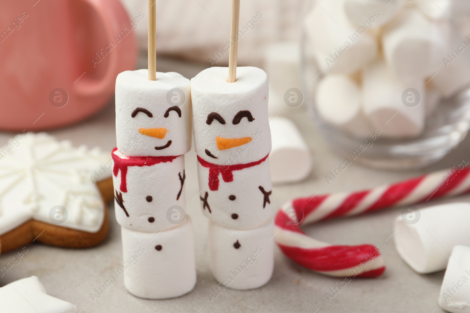 Photo of Funny snowmen made of marshmallows and other sweets on light table, closeup