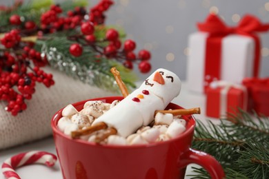 Photo of Funny snowman made with marshmallows in cup of hot drink and Christmas decor, closeup