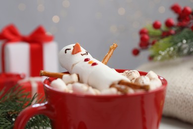 Photo of Funny snowman made with marshmallows in cup of hot drink and Christmas decor, closeup