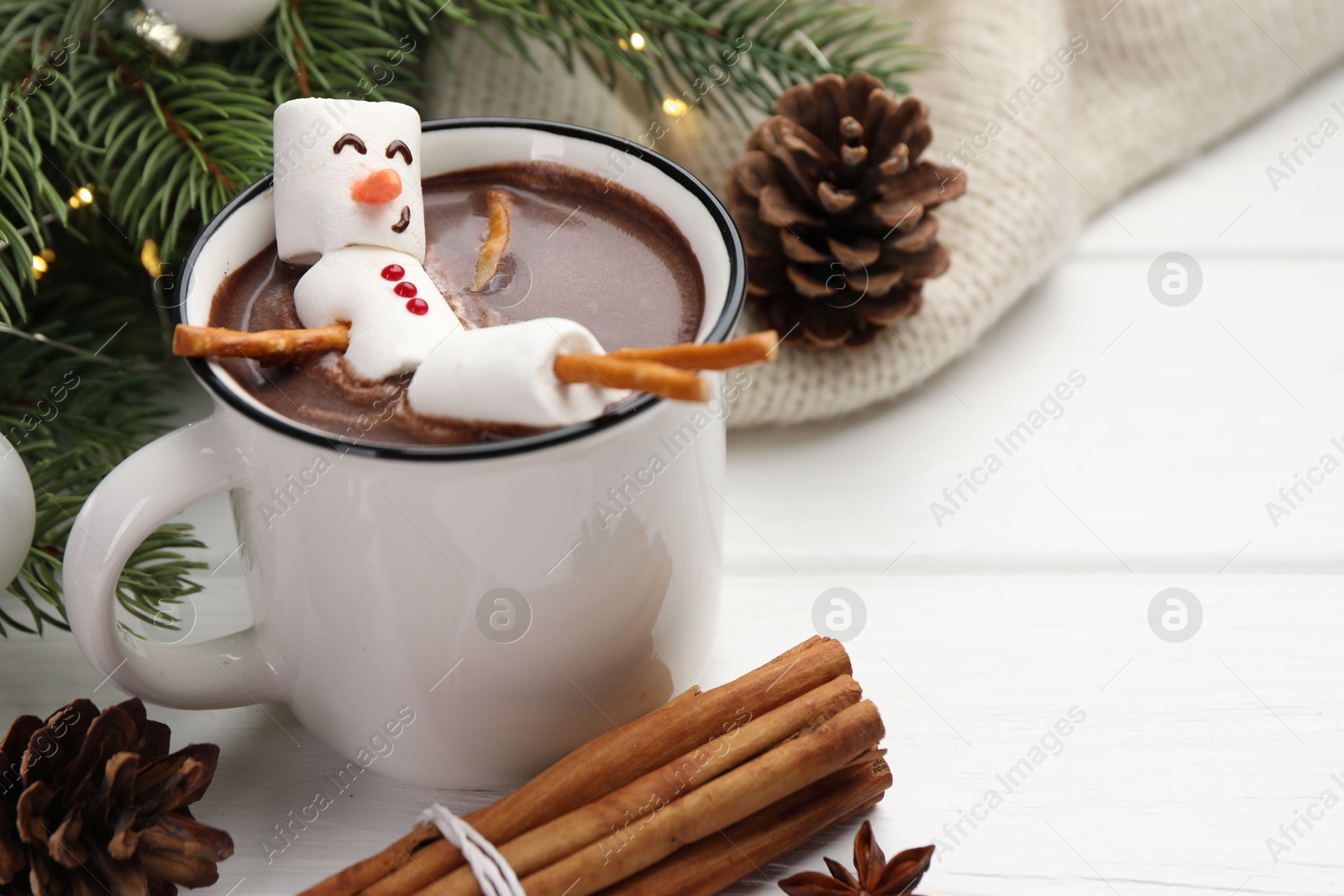 Photo of Funny snowman made with marshmallows in cup of hot chocolate and winter decor on white table