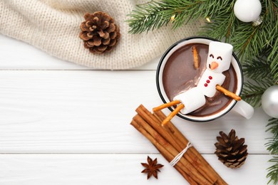 Photo of Funny snowman made with marshmallows in cup of hot chocolate and winter decor on white table, flat lay. Space for text