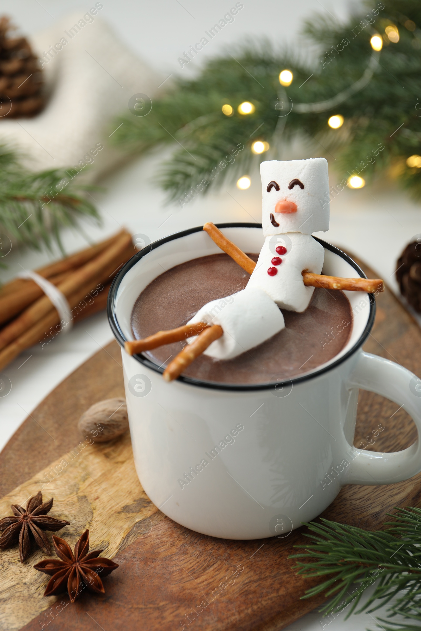 Photo of Funny snowman made with marshmallows in cup of hot chocolate and winter decor on white table