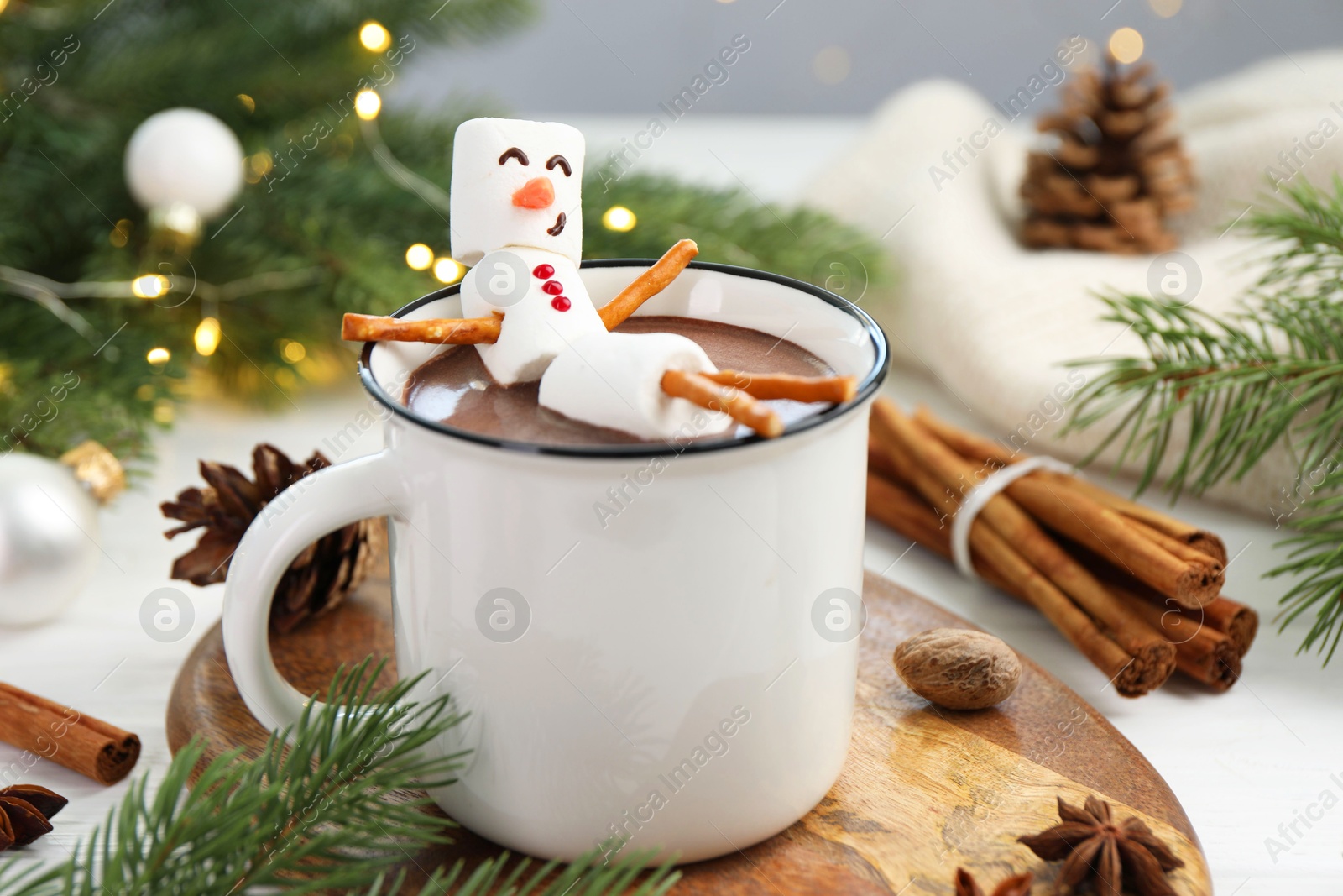 Photo of Funny snowman made with marshmallows in cup of hot chocolate and winter decor on white table