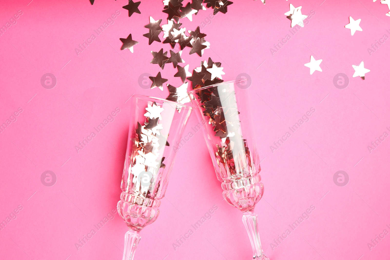 Photo of Wine glasses with confetti on pink background, flat lay. Christmas decor