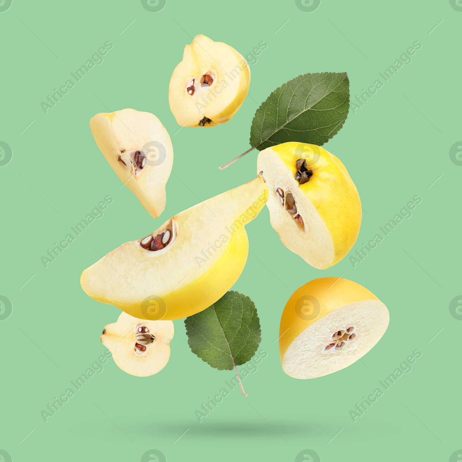 Image of Pieces of fresh quinces and leaves falling on light green background