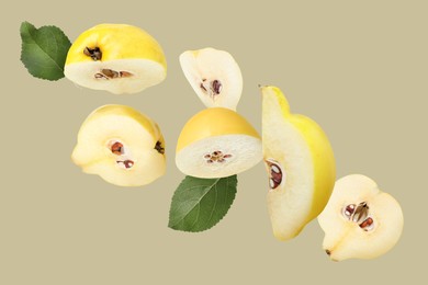 Image of Pieces of fresh quinces and green leaves flying on dark beige background