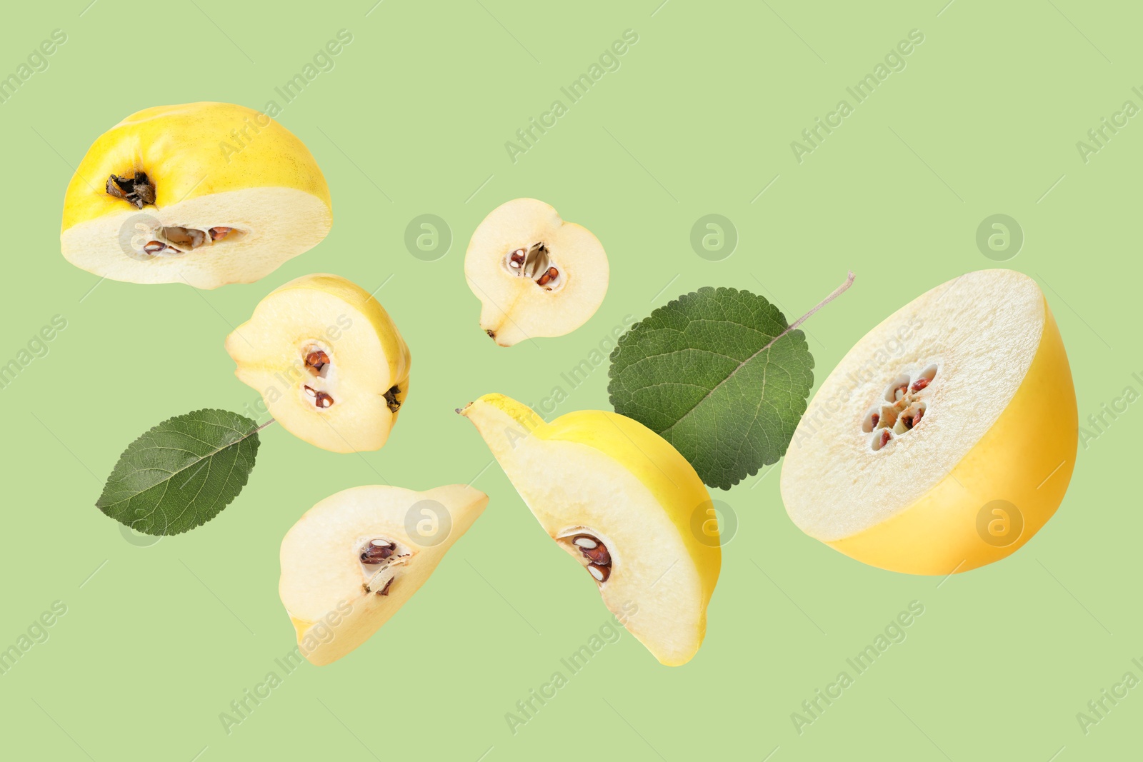 Image of Pieces of fresh quinces and leaves flying on light green background