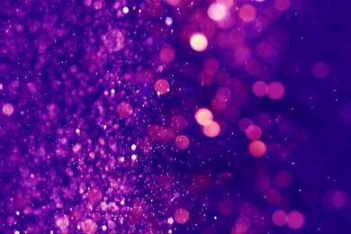 Image of Purple glitter falling on blue background, bokeh effect. Halloween backdrop