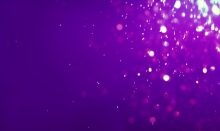 Image of Glitter falling on violet background, bokeh effect. Halloween backdrop. Banner design with space for text