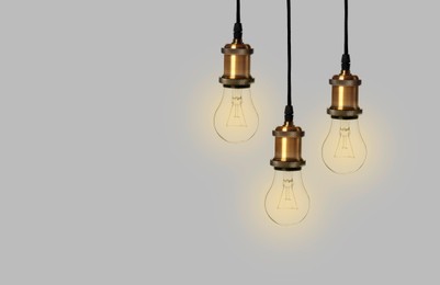 Incandescent light bulbs on gray background, space for text