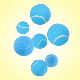 Image of Many light blue tennis balls flying on pale yellow background