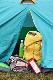 Photo of Tent, backpack, blanket and thermos on green grass outdoors