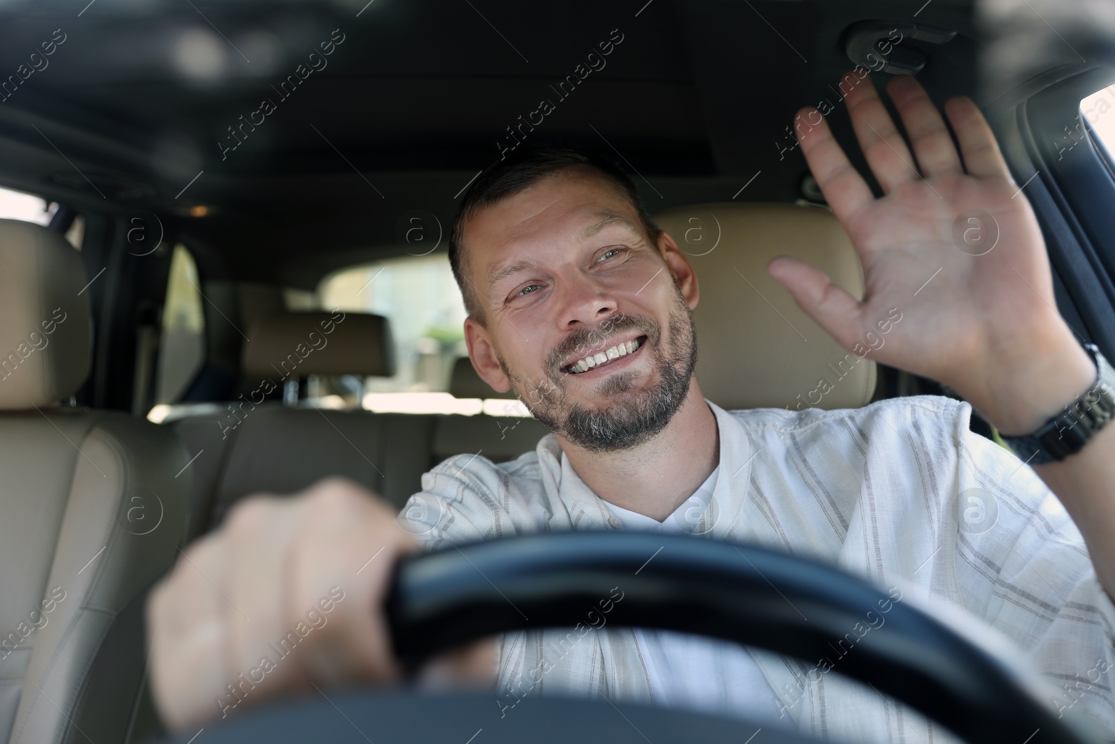 Photo of Smiling man holding steering wheel while driving car, view through windshield