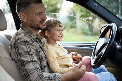 Man with daughter near steering wheel inside car