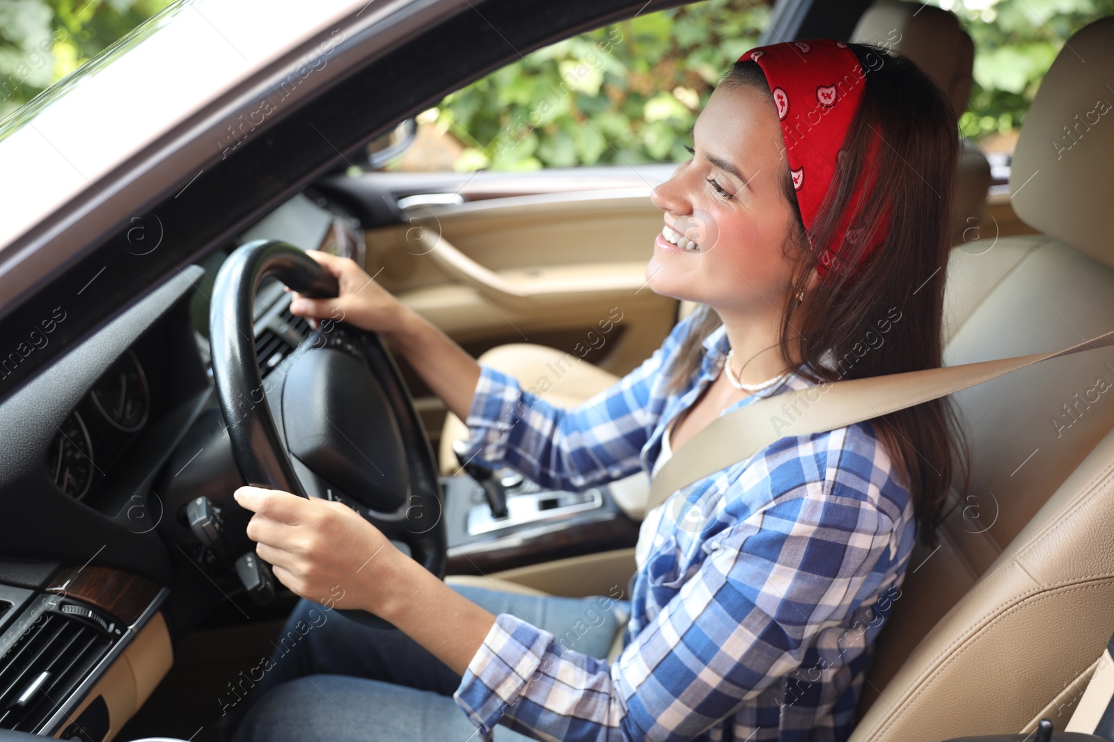 Photo of Smiling woman holding steering wheel while driving car, view from outside