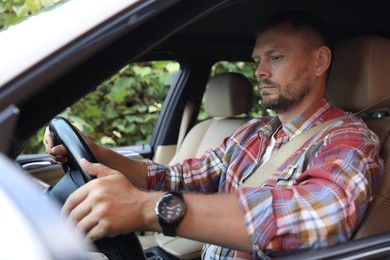 Photo of Man holding steering wheel while driving car, view from outside