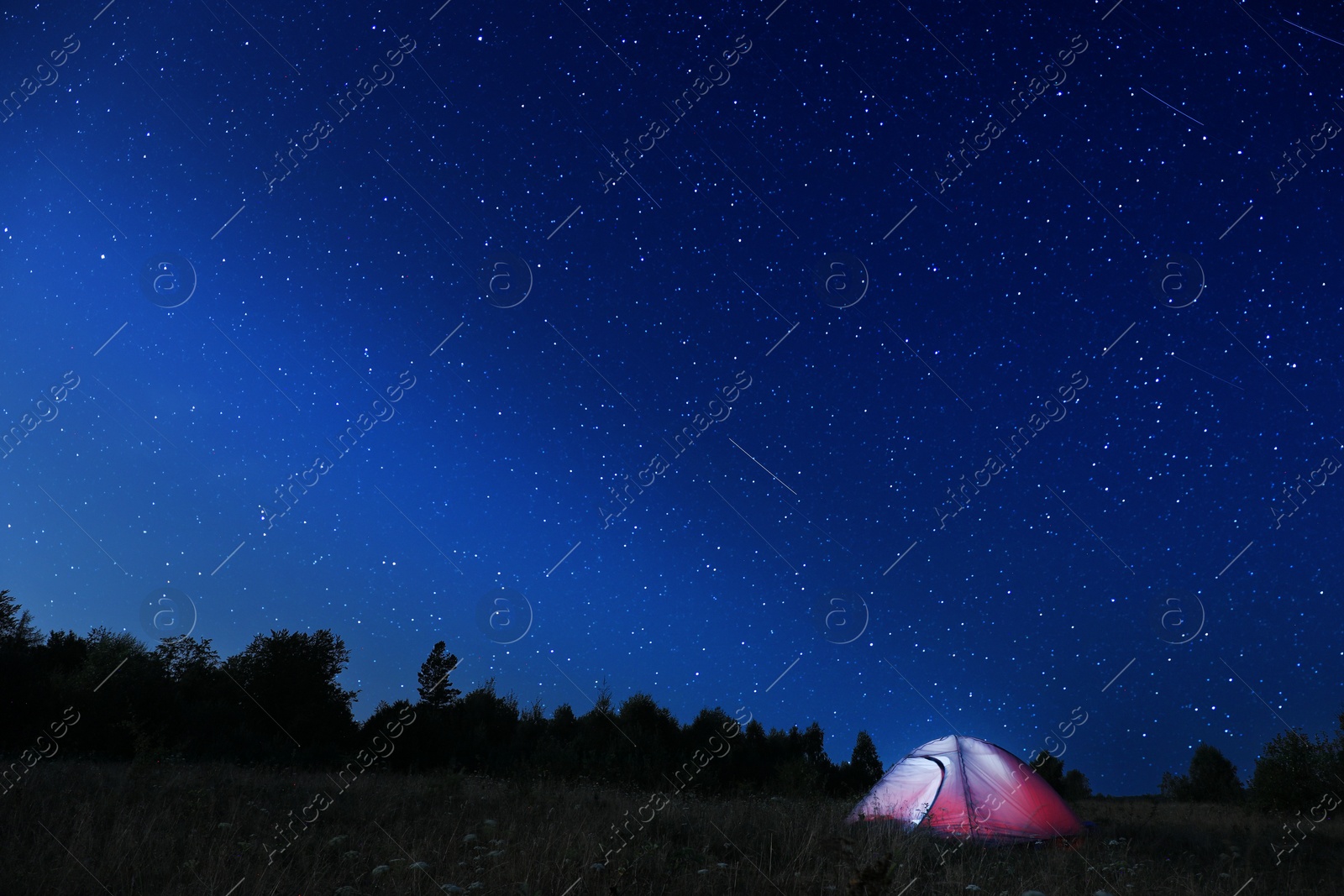 Photo of Modern camping tent in wilderness at night, slow shutter speed effect