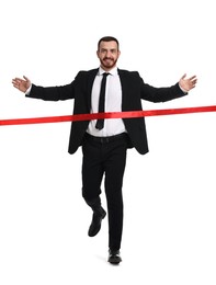 Young businessman in suit crossing red finish line on white background