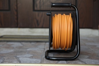 Photo of One extension cord reel on pavement outdoors, space for text