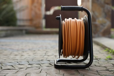 One extension cord reel on pavement outdoors, space for text